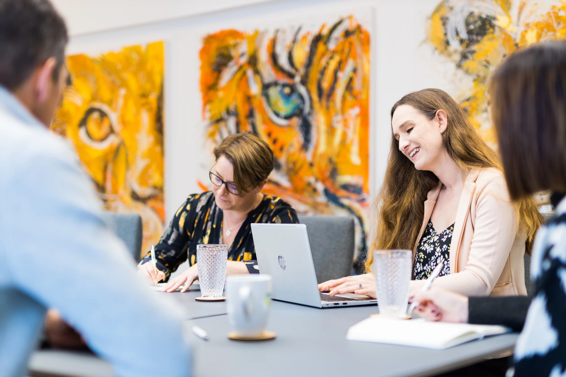 Colour photo of a group of people sitting at a table looking at a laptop