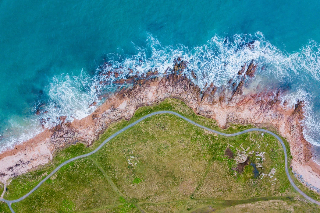 Aerial top down drone photo of rugged coast with sea and walking trail