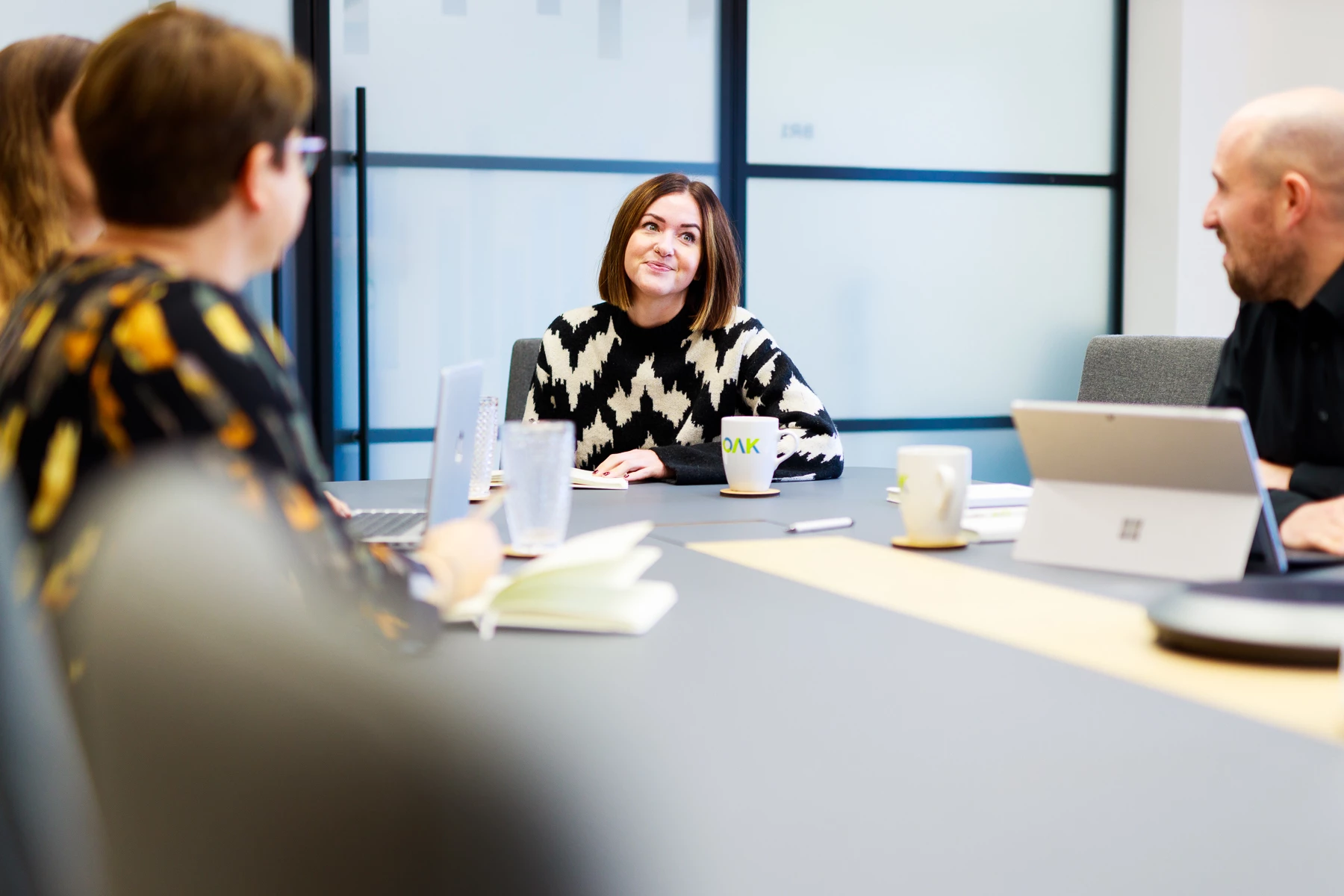 Colour photo of a group of people sitting around a table with laptops