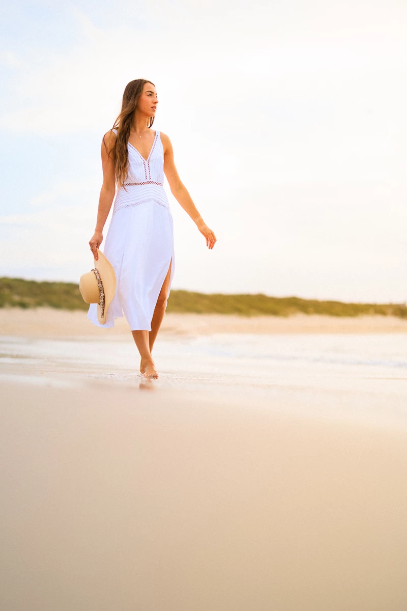 Colour photo of a person in a dress walking on a beach