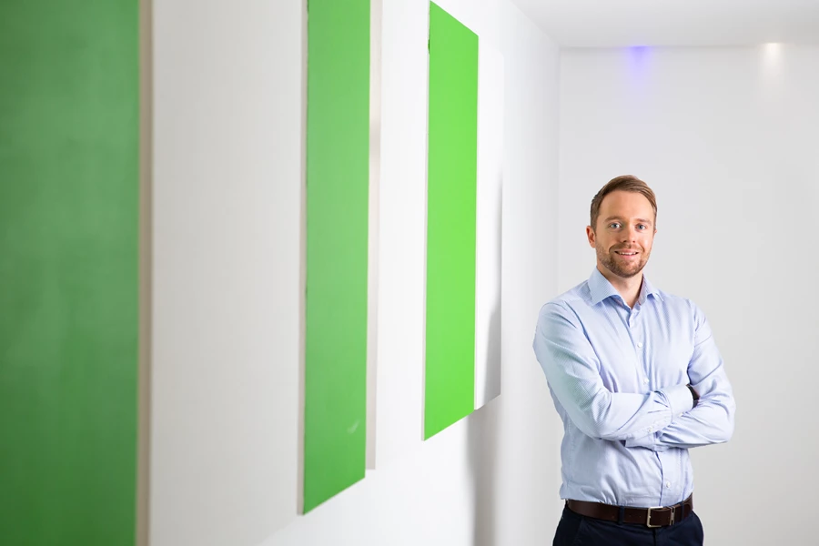 Corporate business portrait head shot of man next to striped green wall