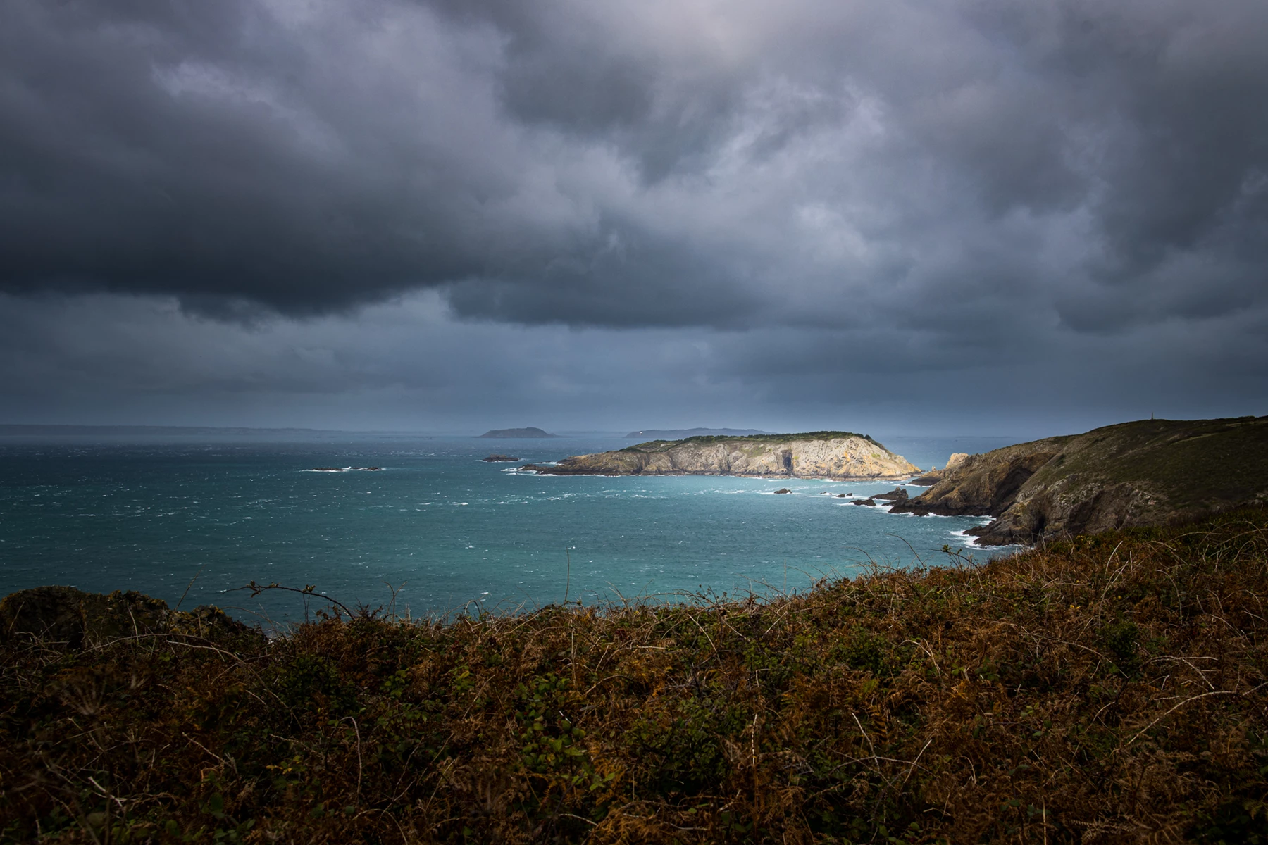 Colour photo of a body of water with land and a land with a hill in the back