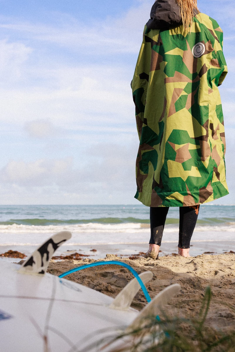 Colour photo of a person wearing a green dress and standing on a beach