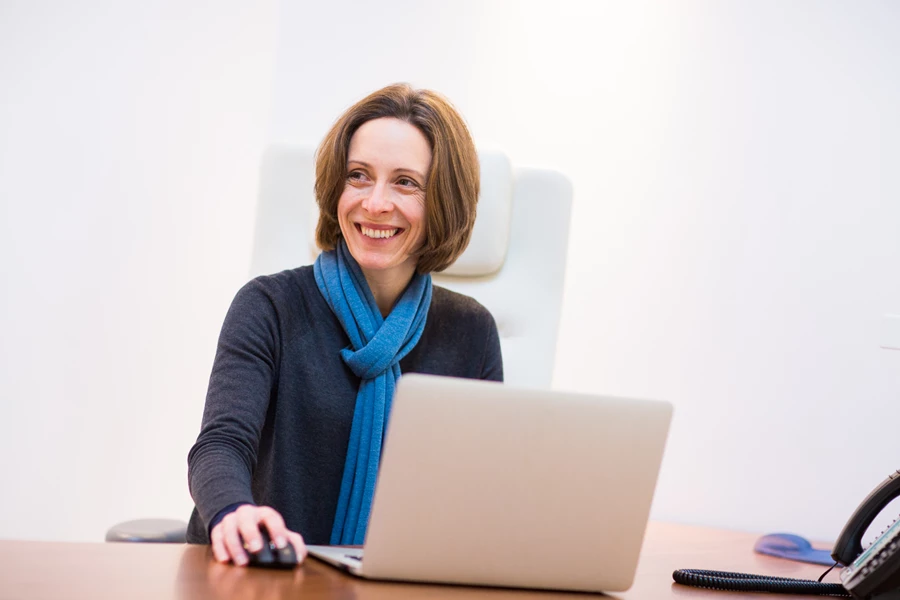 Corporate portrait head shot of woman sitting at a desk with a laptop
