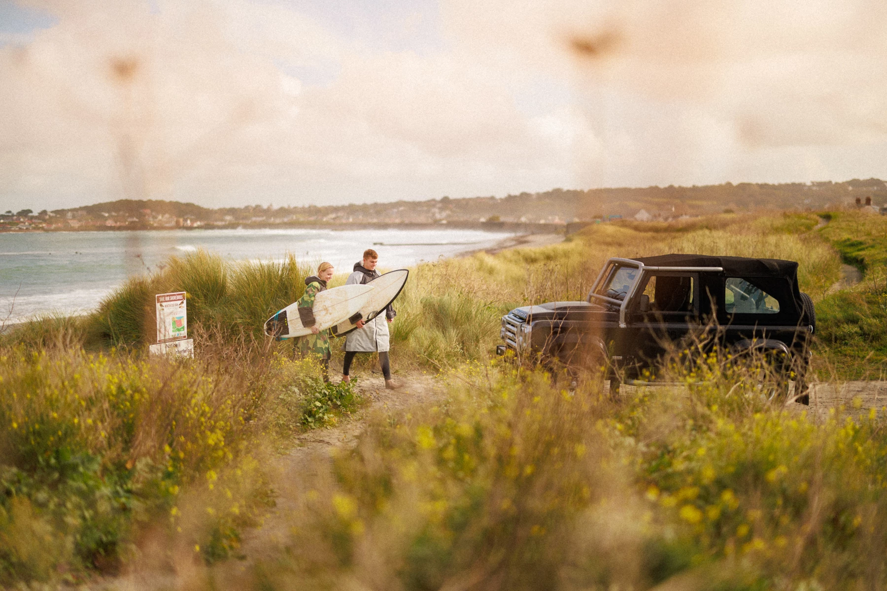 Colour photo of a group of people carrying surfboards