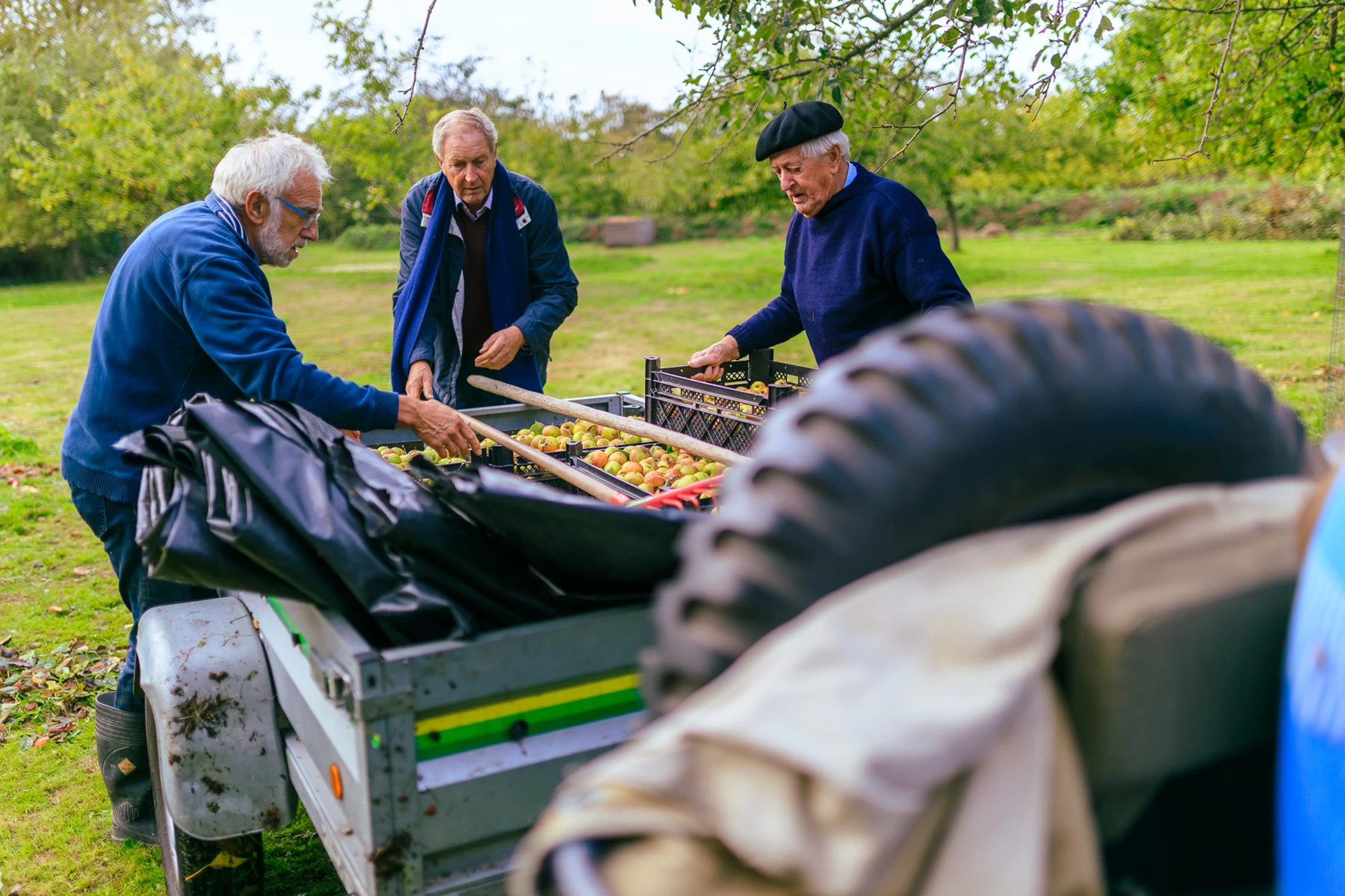 Colour photo of a group of men standing around a car with food on it