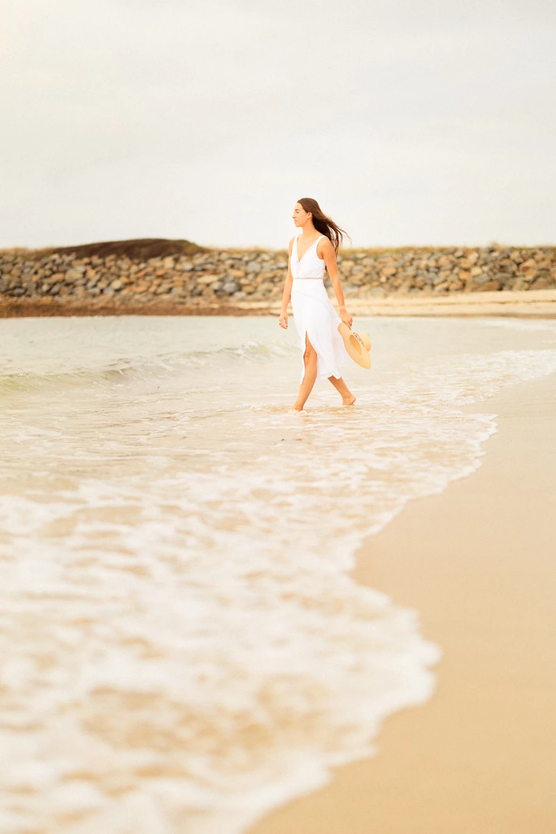 Colour photo of a person walking on a beach