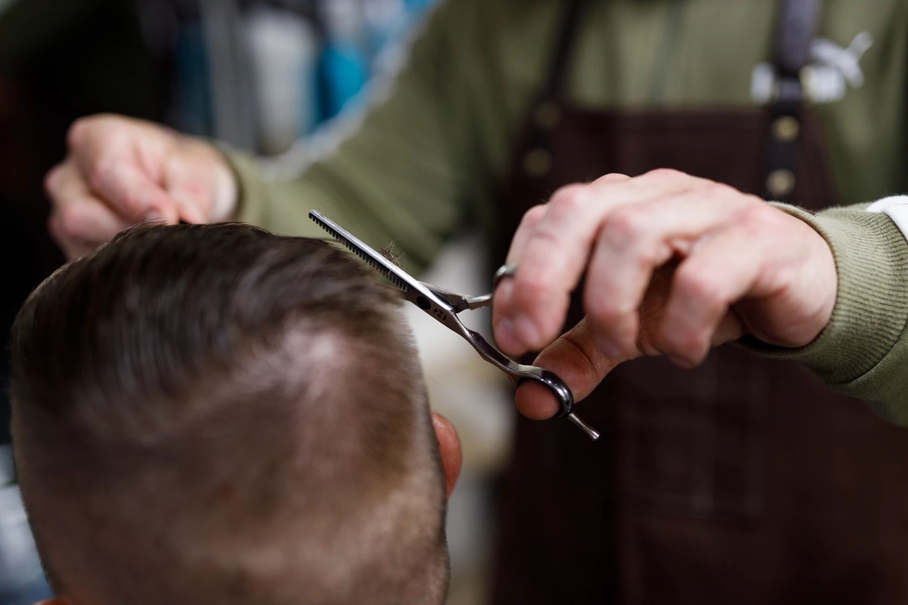 Colour photo of a man cuts another man's hair with scissors