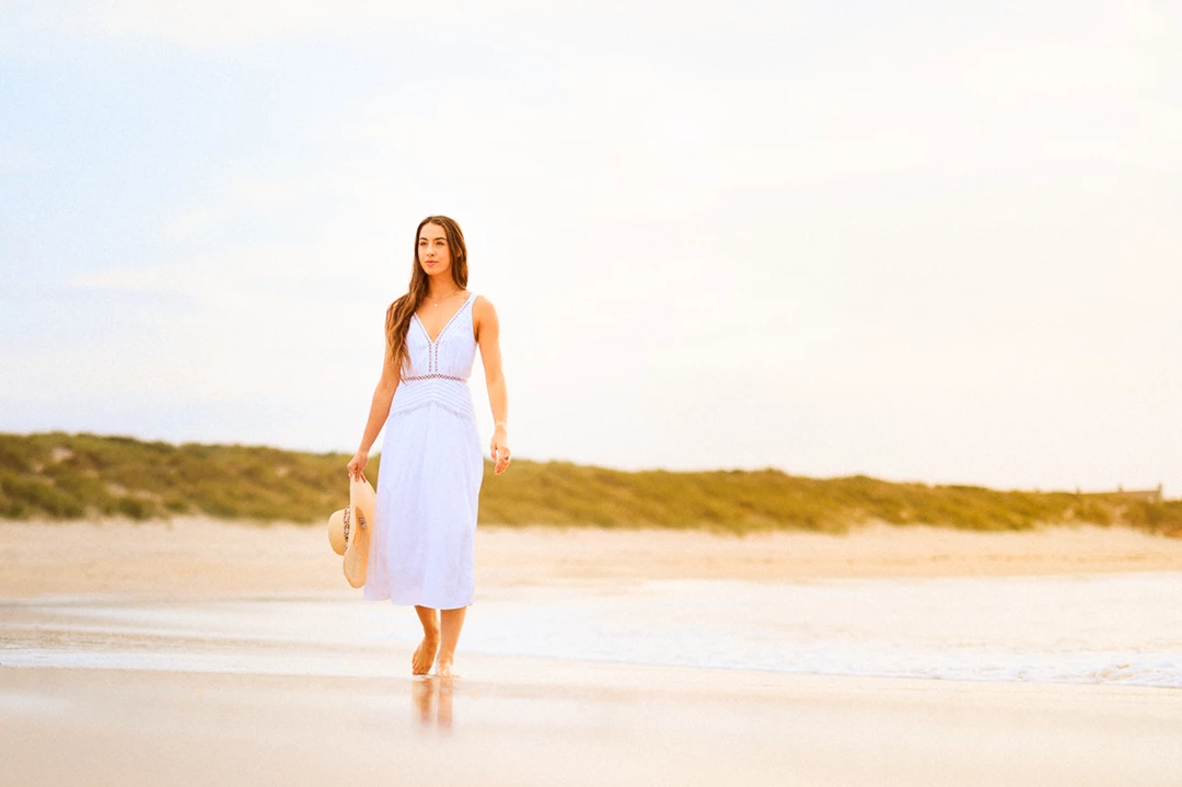Colour photo of a person walking on a beach