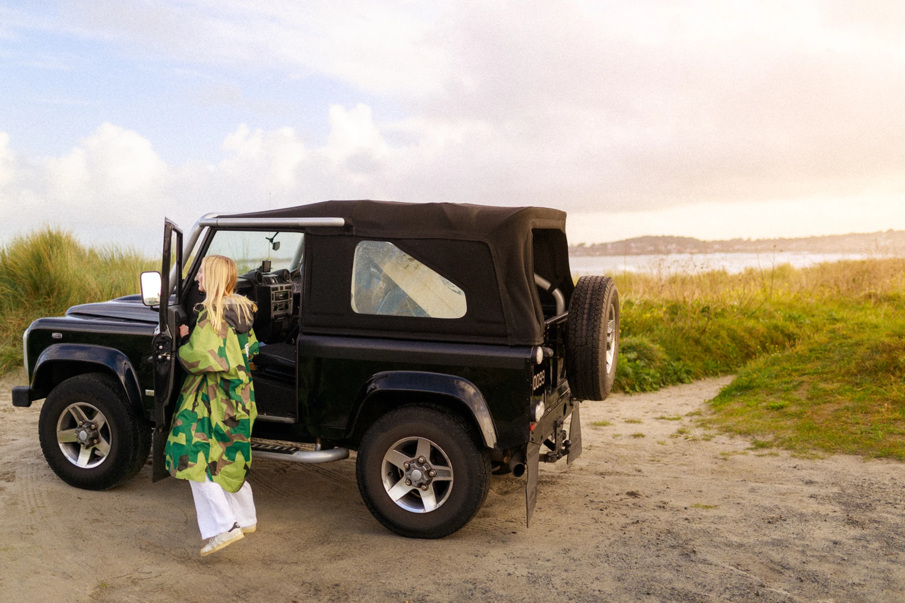 Colour photo of a person standing next to a car