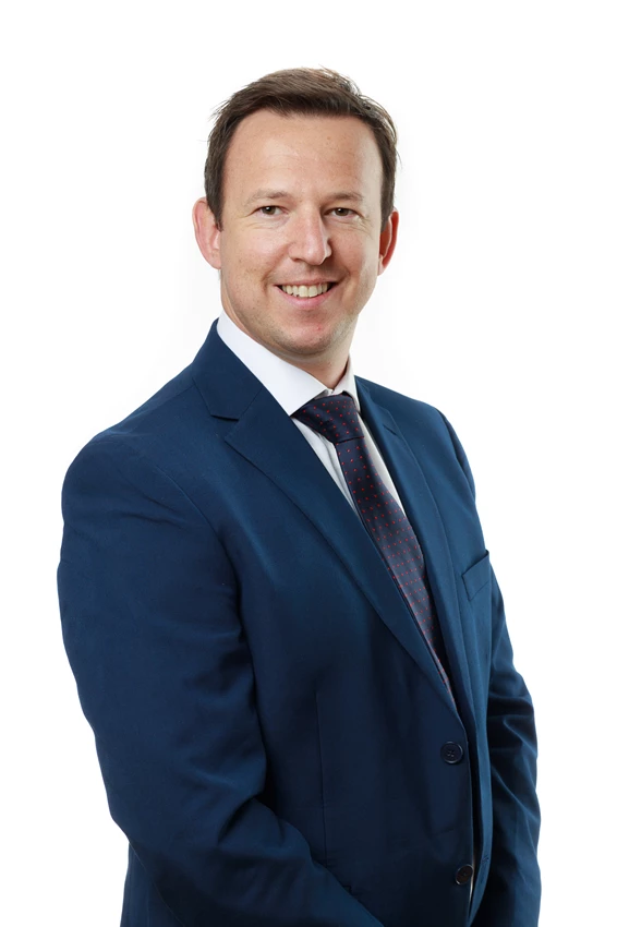 Colour photo of a man in a suit smiling