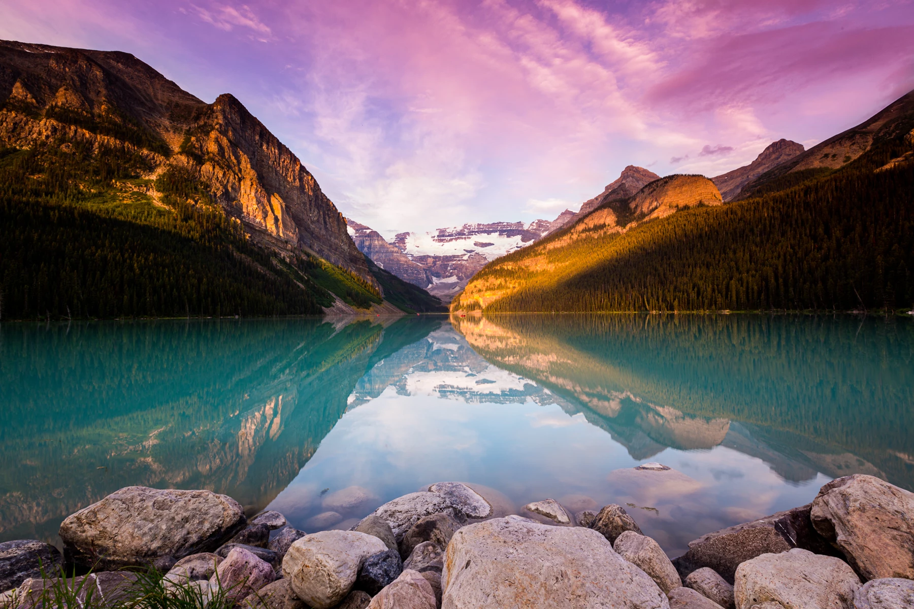 Colour photo of a body of water with rocks and mountains in the background