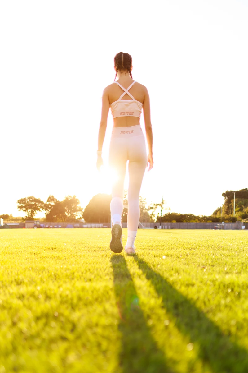 Colour photo of a person walking on a grass field