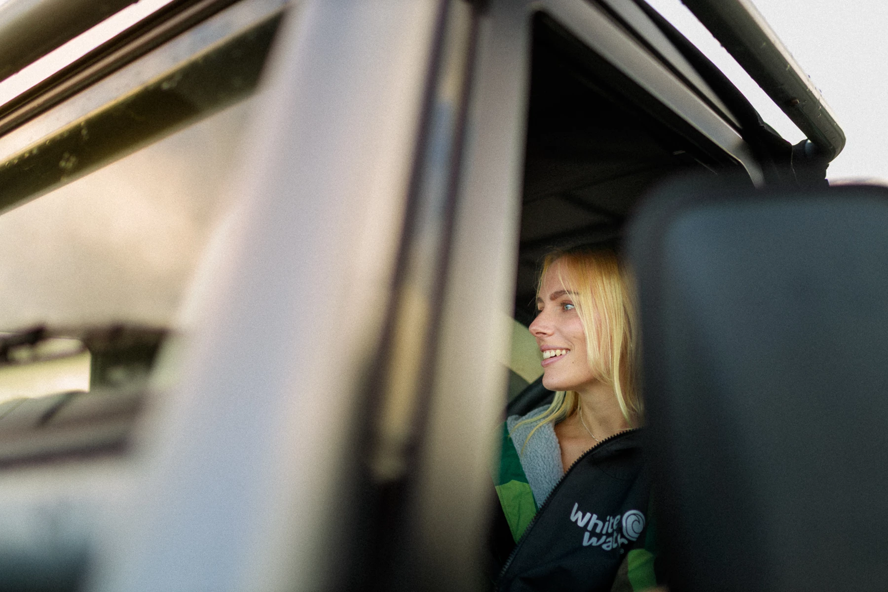 Colour photo of a person smiling and looking out of a train window