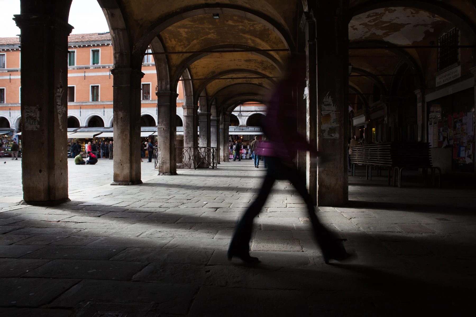Colour photo of a person walking under a building