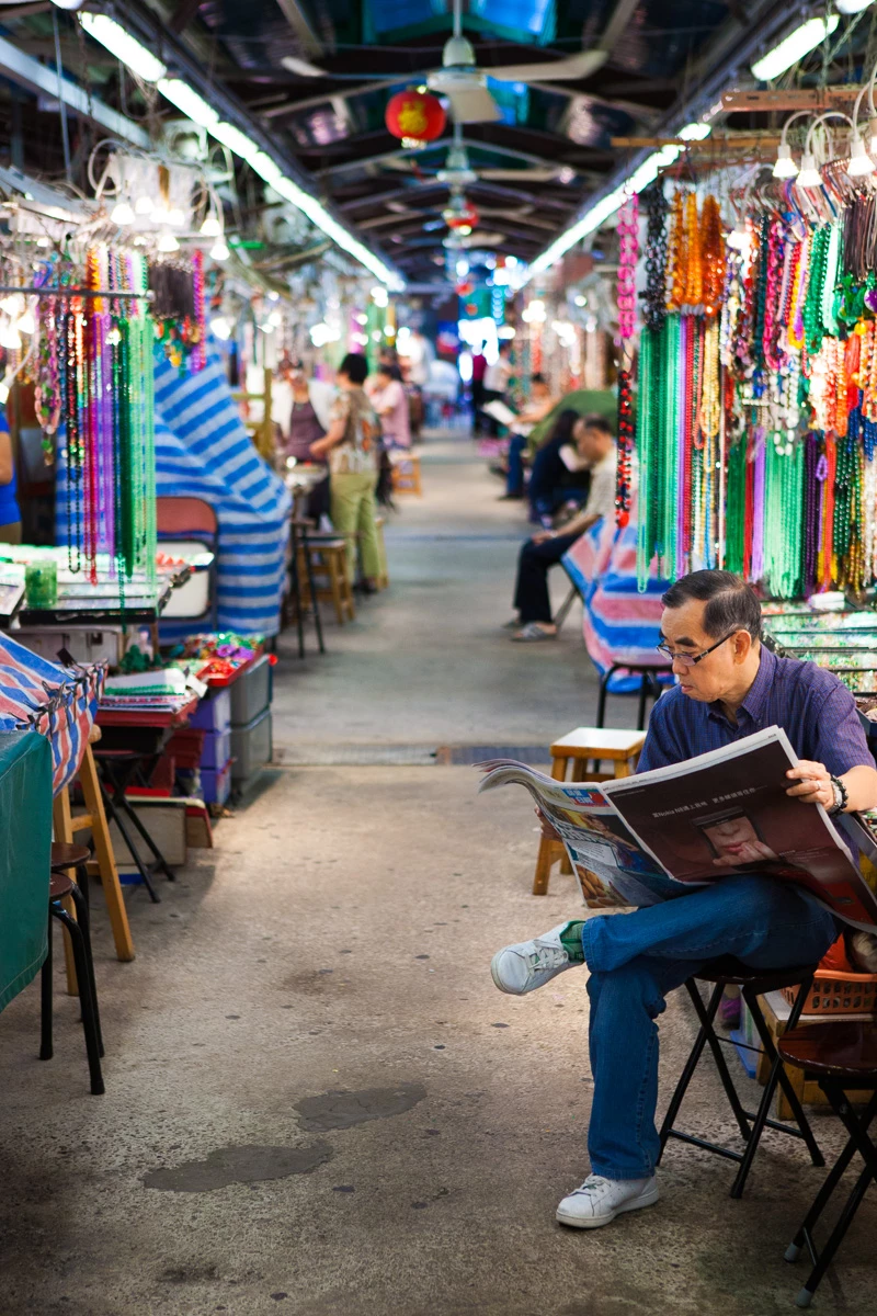 Colour photo of a person sitting in a chair playing a guitar in a store