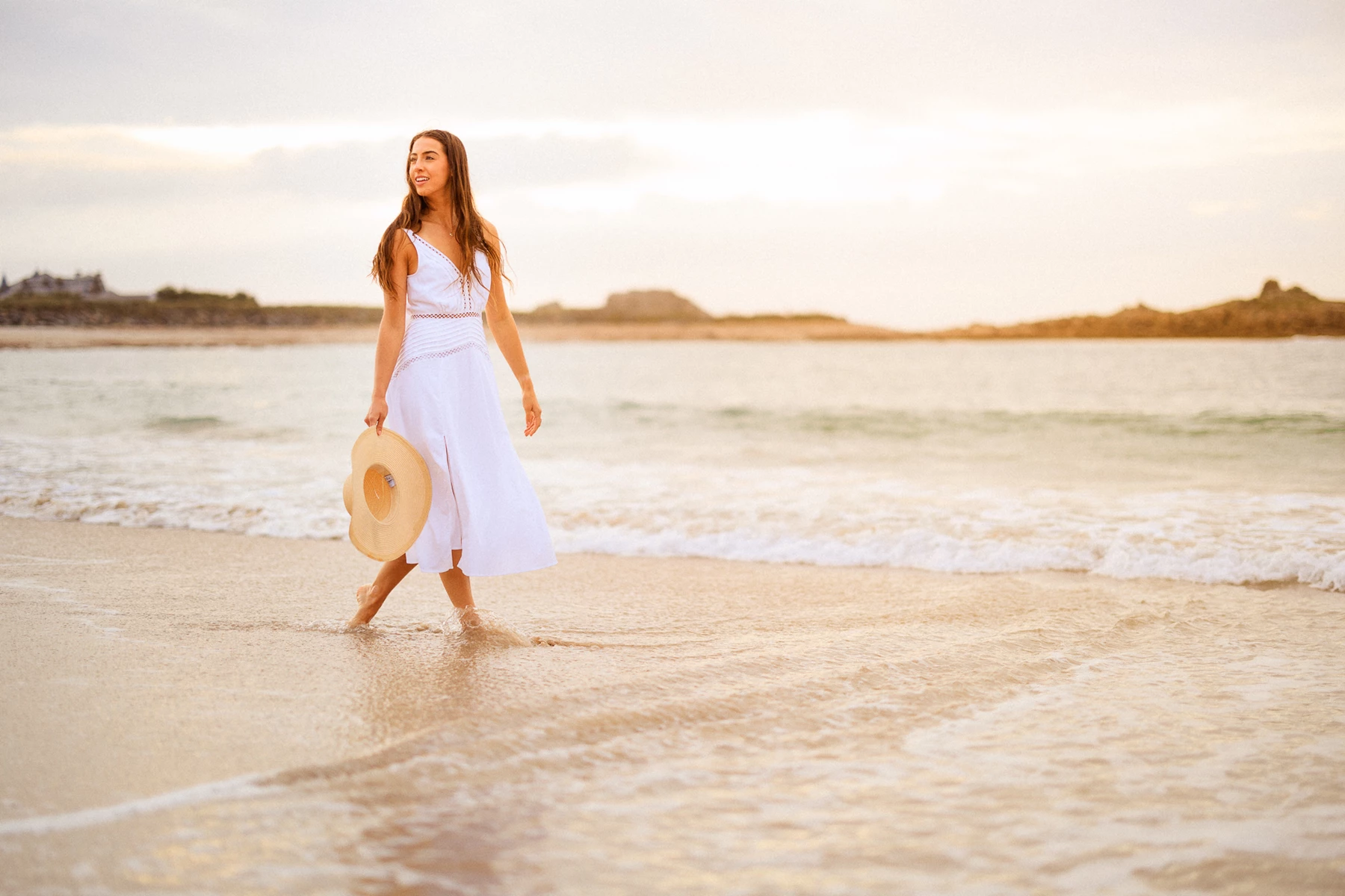 Colour photo of a man in a white dress walking on the beach