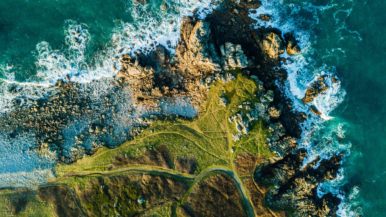 Aerial top down drone photo of rugged cliffs with sea waves crashing