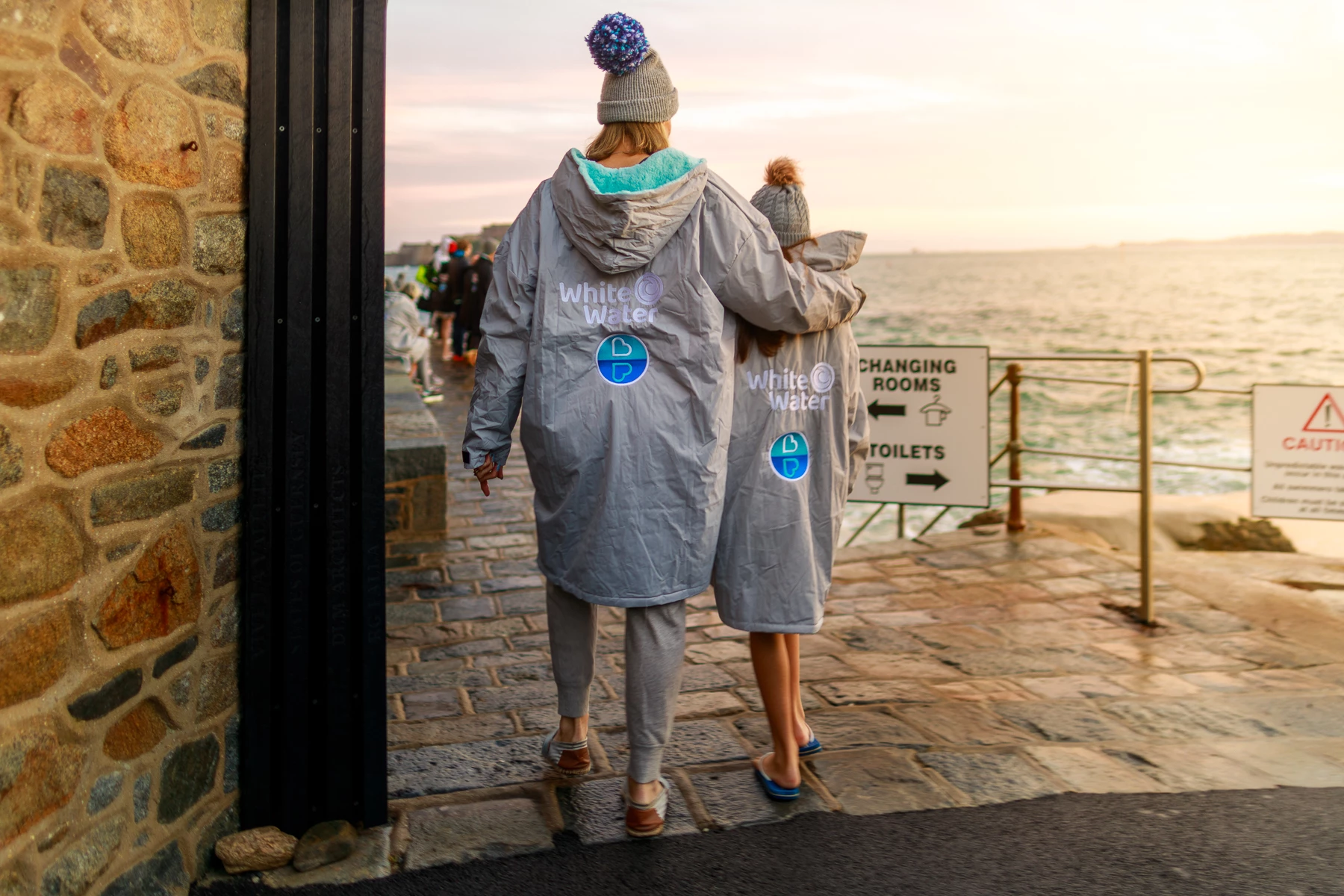 Colour photo of a couple people walking on a sidewalk