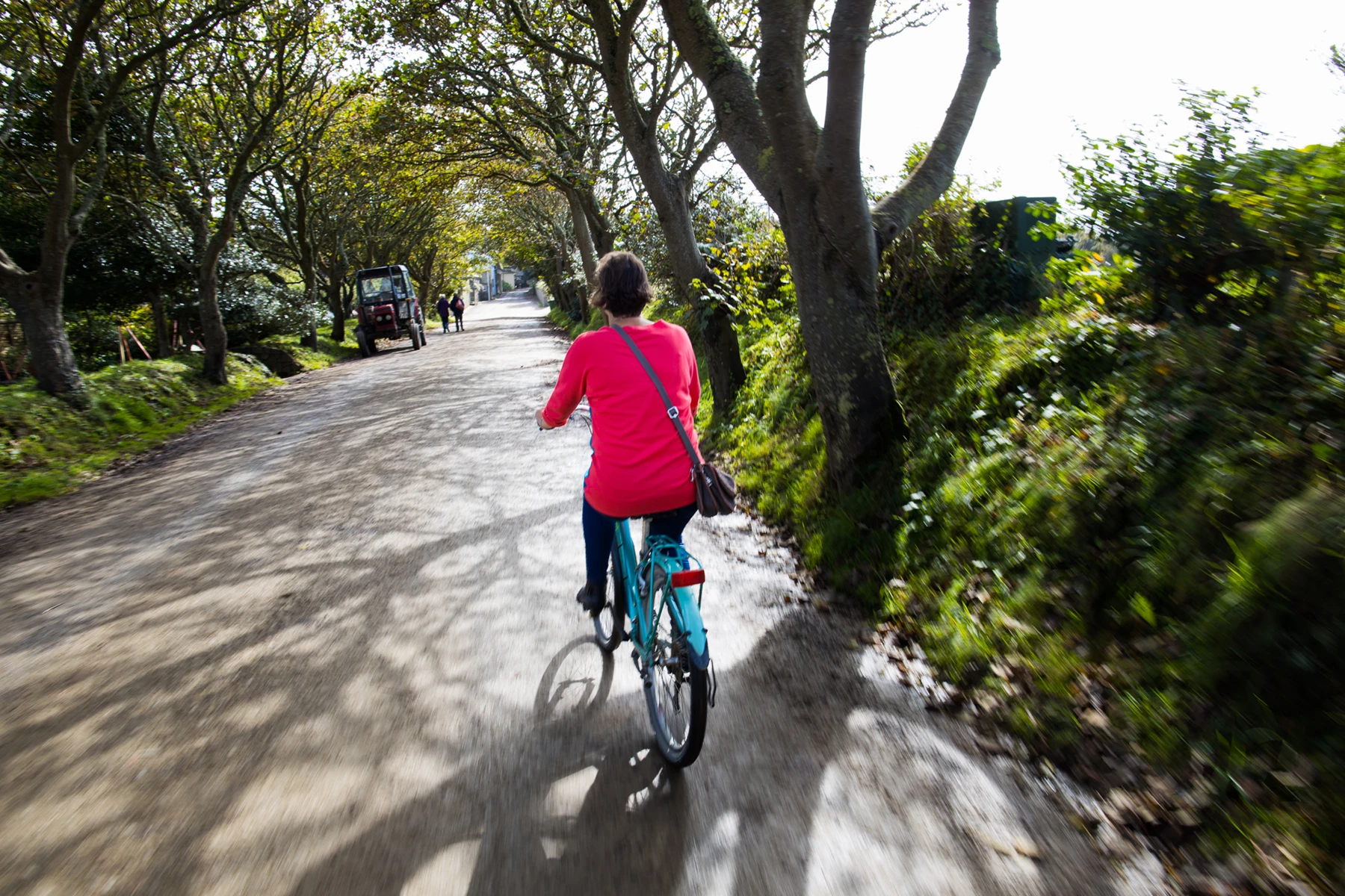 Colour photo of a woman riding a bicycle on a dirt road
