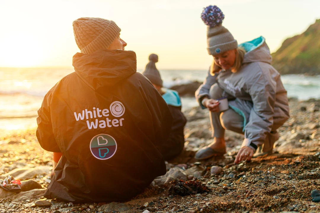 Colour photo of a couple of people sitting on the beach