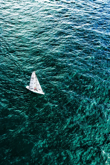 Colour photo of a sailing boat sailing in open water, aerial photography