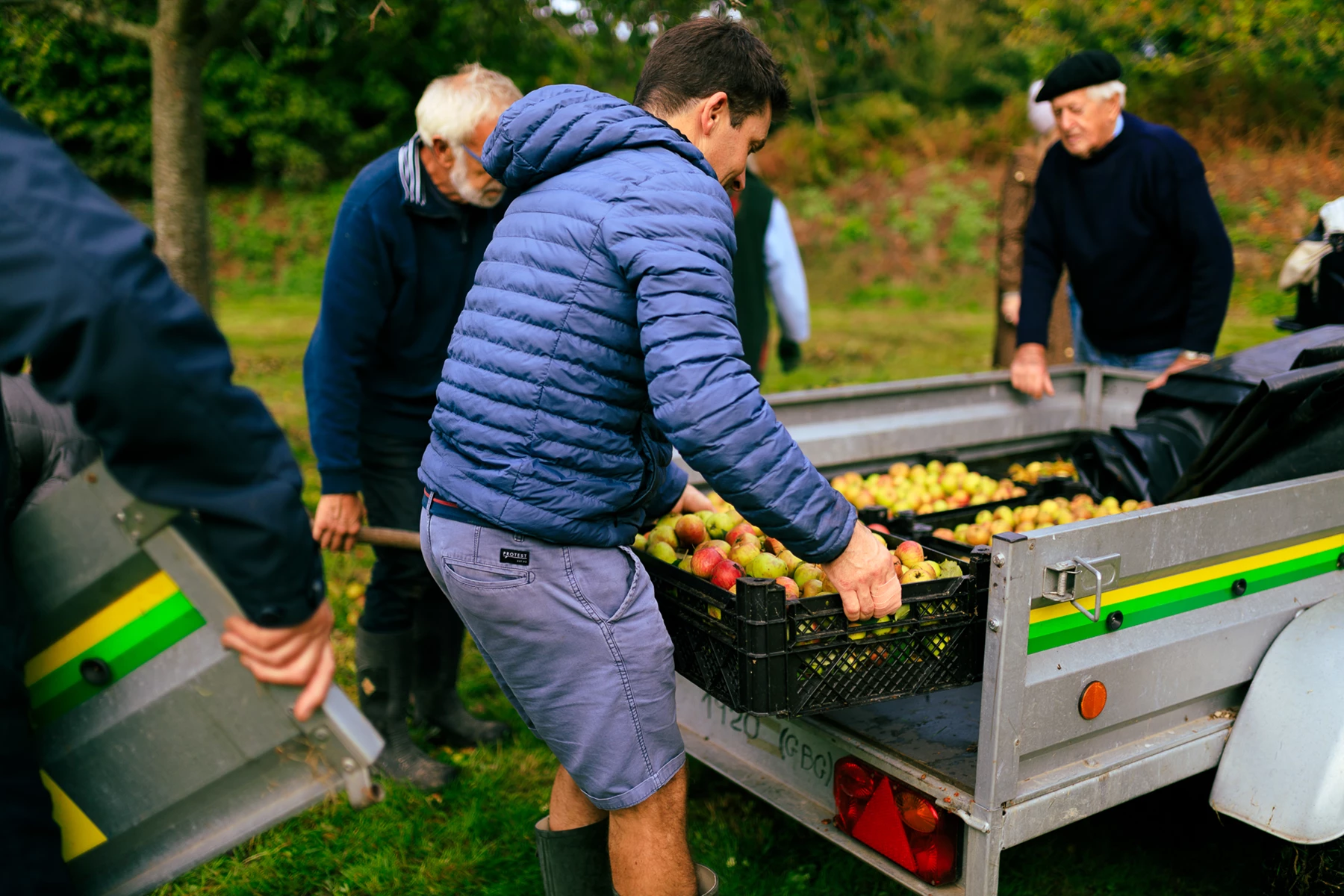 Colour photo of a group of people standing around a grill with fruit