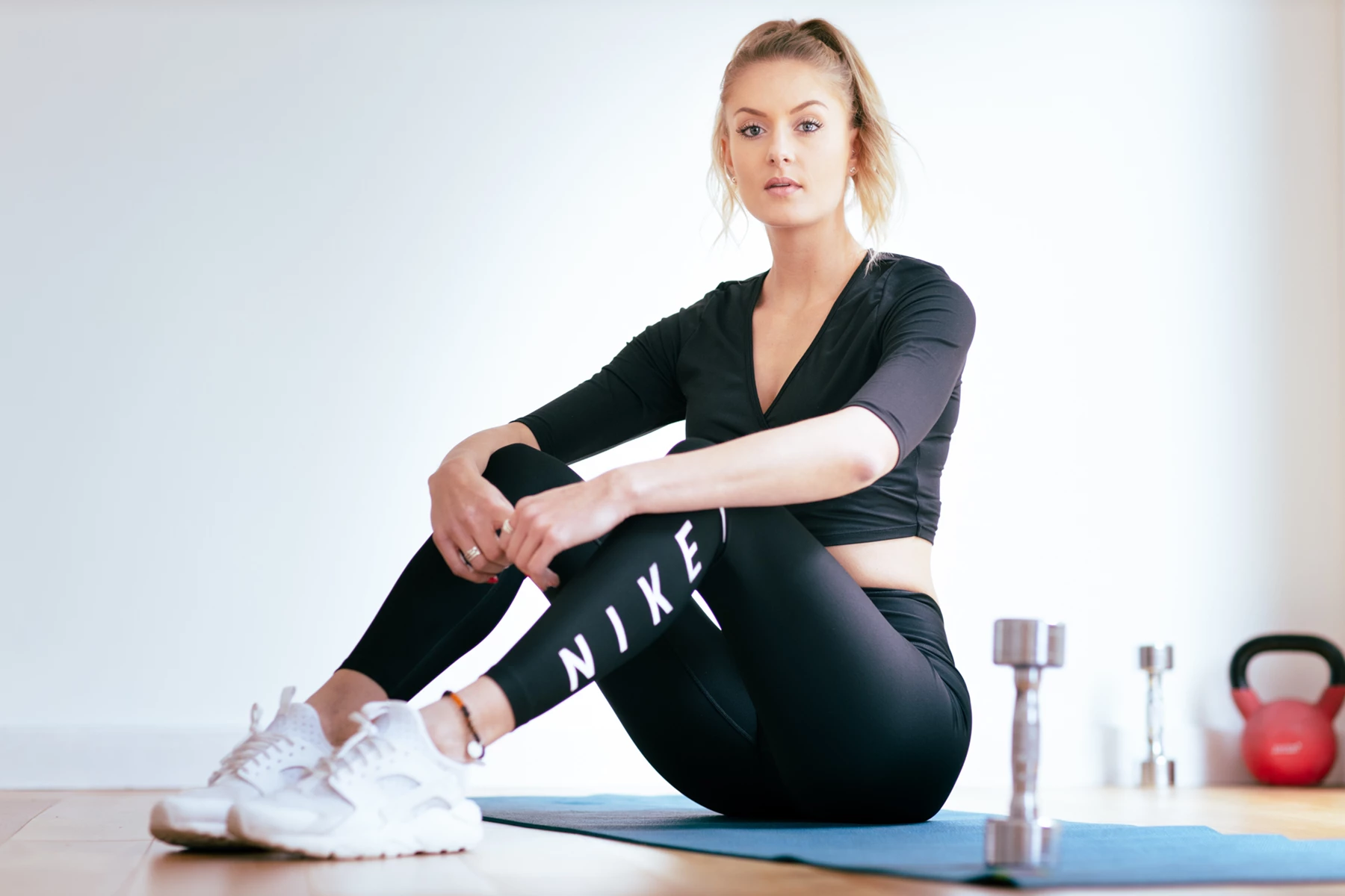 Studio lifestyle photo of a woman sitting in gym clothing